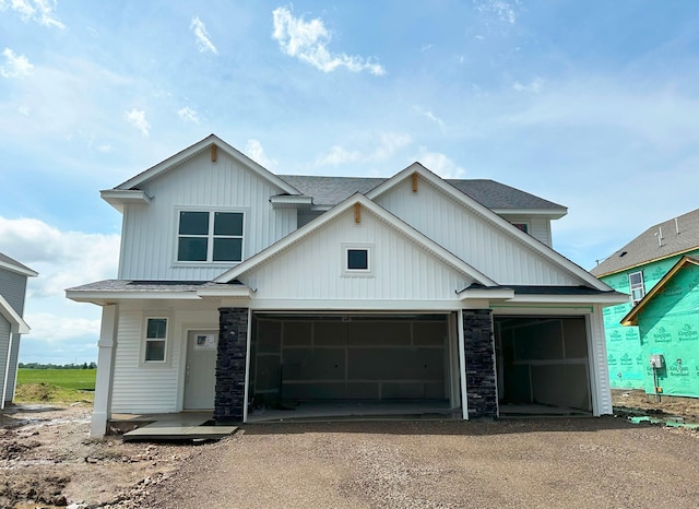2461 Jandell Ave NE, Saint Michael, MN 55376 - view of front of house with driveway, board and batten siding, stone siding, an attached garage, and a shingled roof