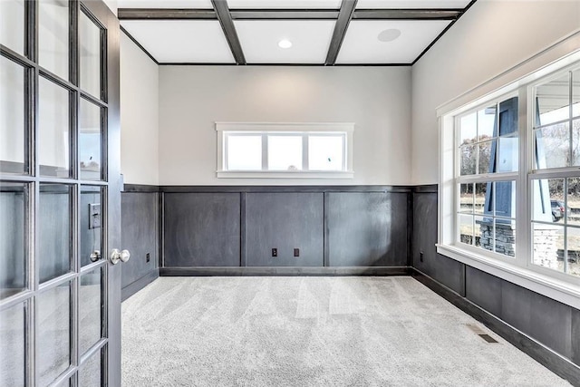 unfurnished room with carpet floors, a wainscoted wall, and a decorative wall