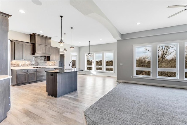 kitchen with stainless steel gas cooktop, decorative backsplash, dark brown cabinetry, light wood finished floors, and recessed lighting