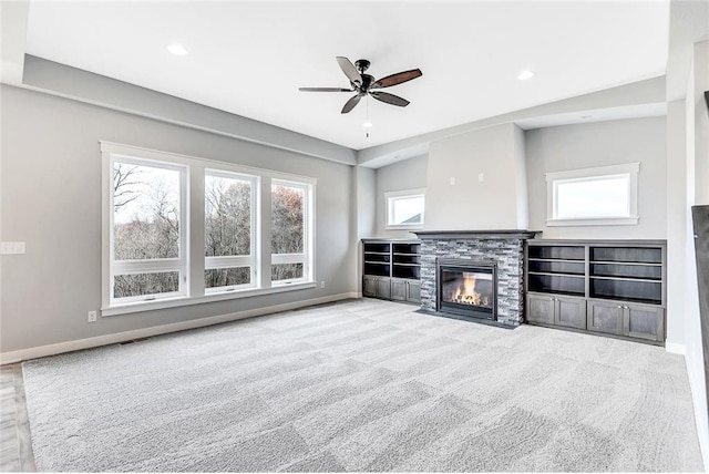 unfurnished living room featuring baseboards, a stone fireplace, a ceiling fan, carpet flooring, and recessed lighting