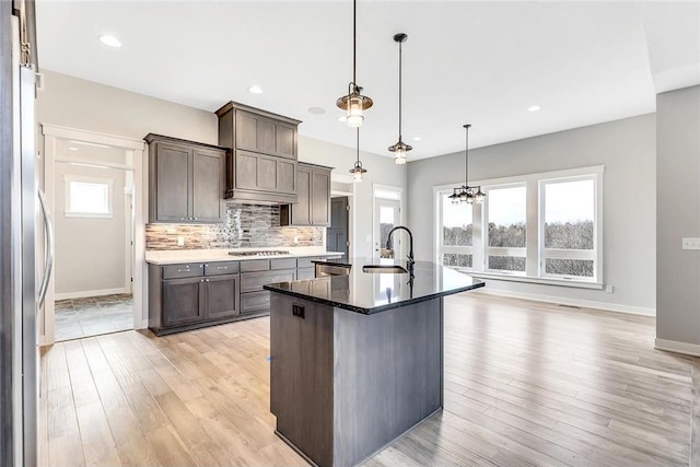 kitchen with a sink, light wood-style floors, baseboards, tasteful backsplash, and recessed lighting