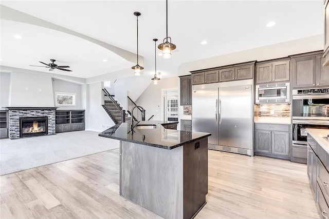 kitchen with built in appliances, light wood finished floors, ceiling fan, recessed lighting, and a sink