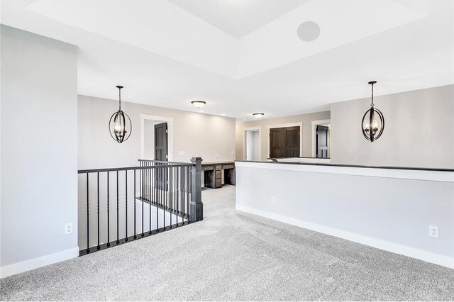empty room featuring a chandelier, baseboards, and light carpet