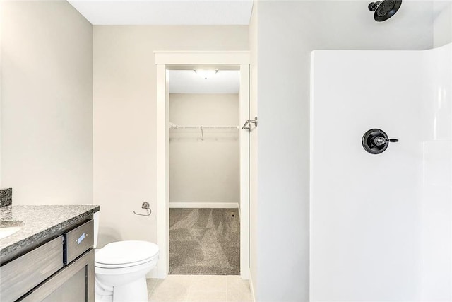 bathroom with a spacious closet, vanity, tile patterned floors, toilet, and a shower
