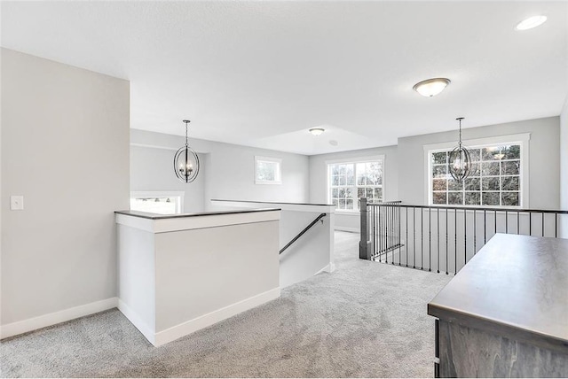 corridor featuring a chandelier, an upstairs landing, carpet flooring, and baseboards
