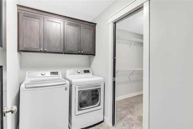 clothes washing area with separate washer and dryer, cabinet space, light colored carpet, a textured ceiling, and baseboards