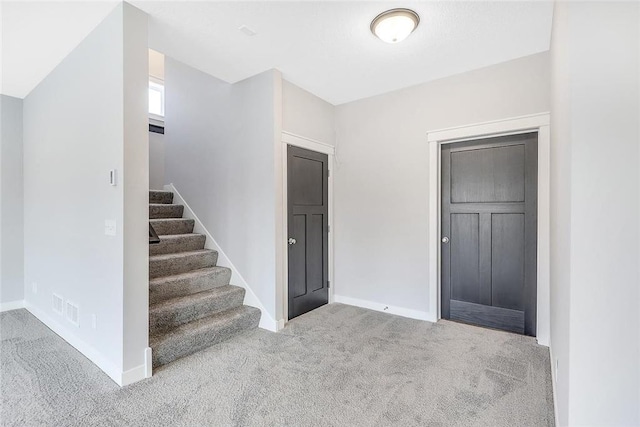 foyer with carpet floors, stairway, and baseboards