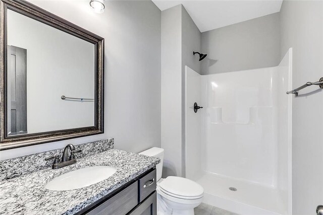 full bathroom featuring a shower stall, toilet, and vanity