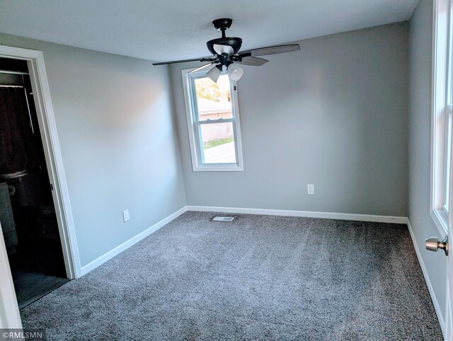 carpeted empty room with ceiling fan and baseboards