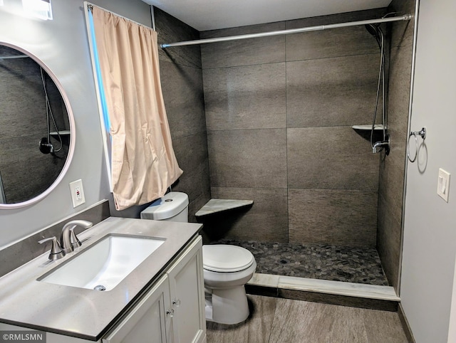 full bath with toilet, a tile shower, and vanity