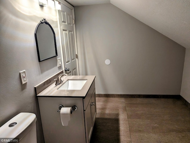 half bathroom with vaulted ceiling, vanity, toilet, and baseboards