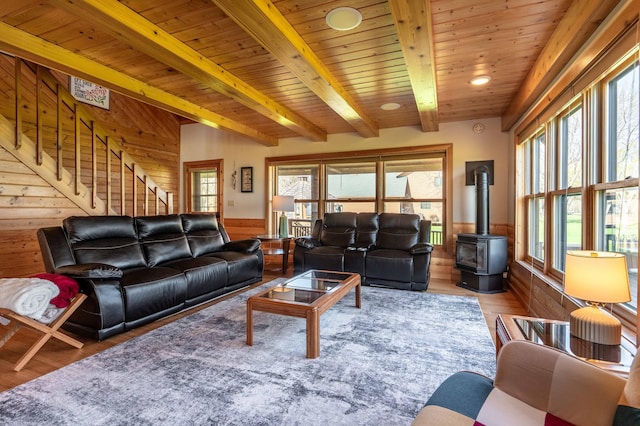 37009 Blarney Beach Rd, Everts Twp, MN 56515 - living room featuring a wood stove, wooden walls, beam ceiling, wood finished floors, and stairs