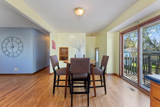 dining area with light wood-style floors, baseboards, and a textured ceiling