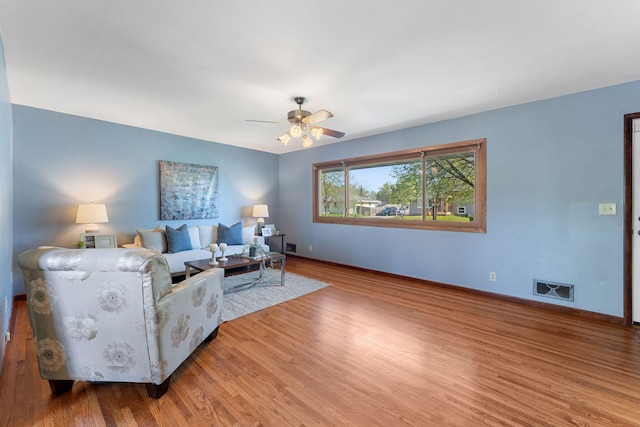 living area with wood finished floors, baseboards, and a ceiling fan
