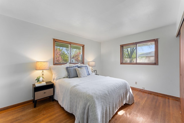 bedroom featuring baseboards, multiple windows, and wood finished floors