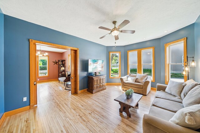 1112 4th St S, Stillwater, MN 55082 - living room with baseboards, a ceiling fan, light wood-style floors, and a chandelier