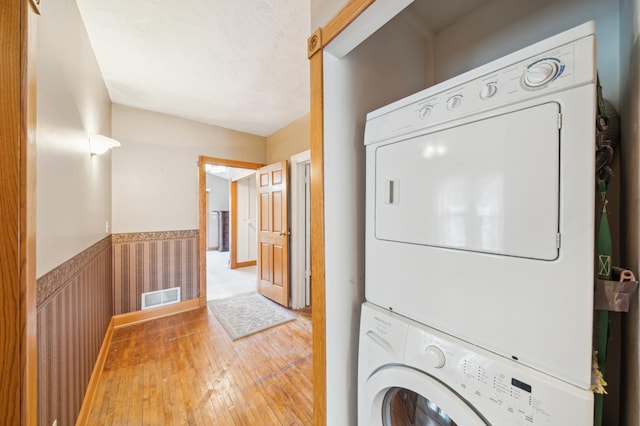 1112 4th St S, Stillwater, MN 55082 - clothes washing area with stacked washing machine and dryer, wainscoting, and hardwood / wood-style floors