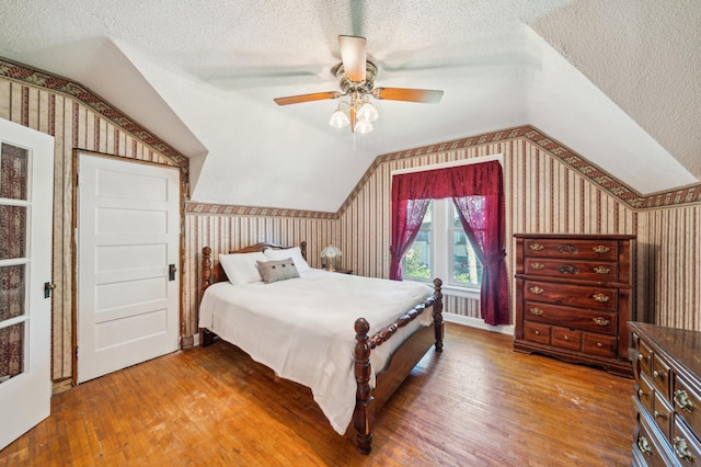 1112 4th St S, Stillwater, MN 55082 - bedroom with wallpapered walls, vaulted ceiling, a textured ceiling, wood finished floors, and a ceiling fan