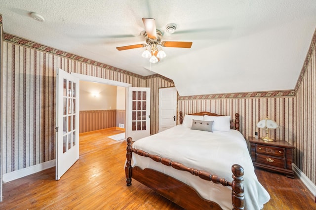 1112 4th St S, Stillwater, MN 55082 - bedroom featuring wallpapered walls, wood finished floors, french doors, wainscoting, and baseboards