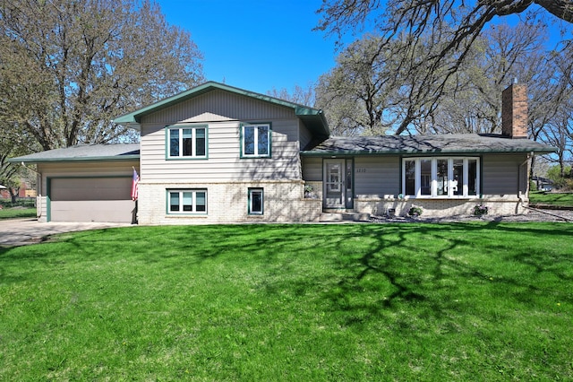 split level home with a chimney, an attached garage, a front lawn, and driveway