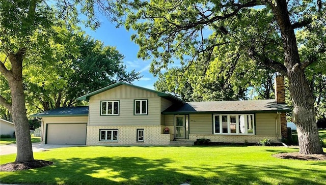 tri-level home with brick siding, an attached garage, a front lawn, a chimney, and driveway