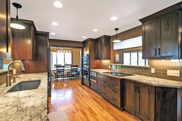 kitchen featuring a sink, black electric stovetop, light wood-type flooring, dark brown cabinetry, and tasteful backsplash