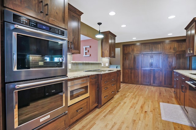 kitchen featuring stainless steel appliances, light wood-style floors, tasteful backsplash, light stone counters, and dark brown cabinetry