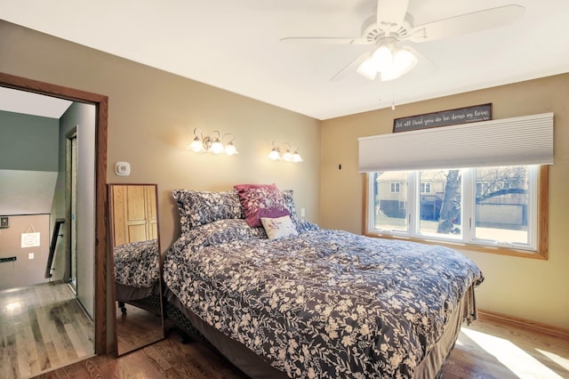 bedroom featuring wood finished floors, a ceiling fan, and baseboards