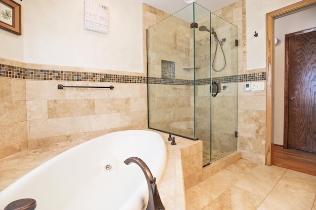 full bathroom with a shower stall, a tub with jets, and tile walls