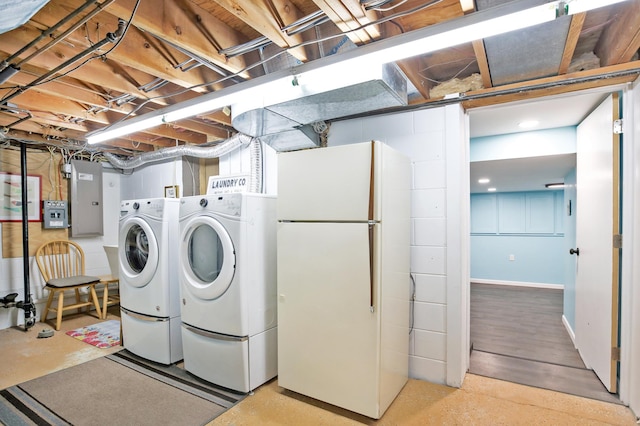 clothes washing area with washing machine and dryer, electric panel, and baseboards