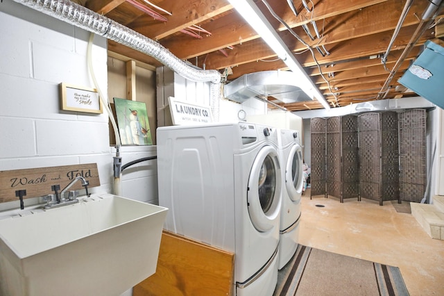 clothes washing area featuring washing machine and clothes dryer and concrete block wall