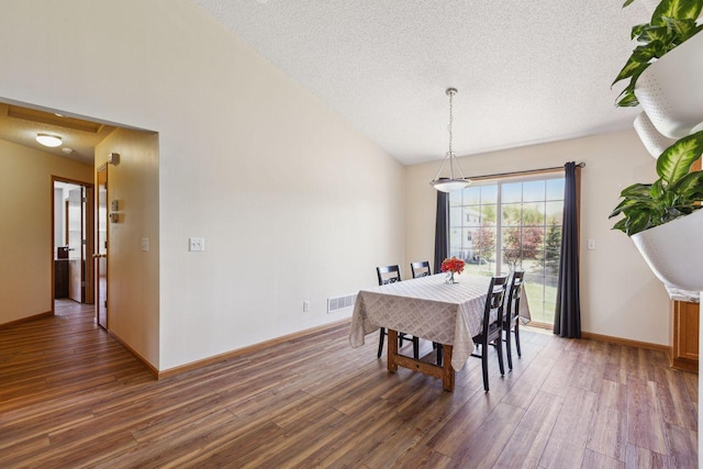 dining area with wood finished floors, a textured ceiling, baseboards, and vaulted ceiling