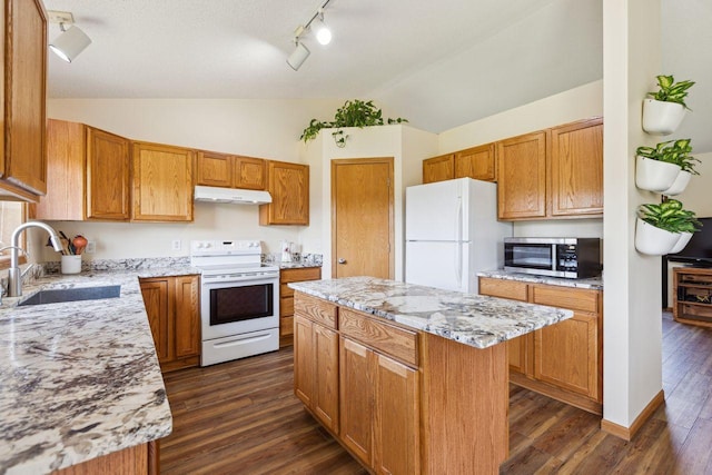 kitchen with white appliances, a sink, under cabinet range hood, lofted ceiling, and rail lighting