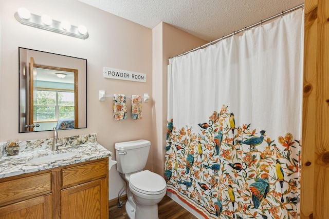 bathroom featuring wood finished floors, a textured ceiling, toilet, vanity, and a shower with curtain