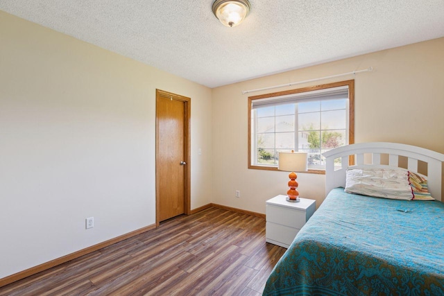 bedroom featuring wood finished floors, a textured ceiling, and baseboards