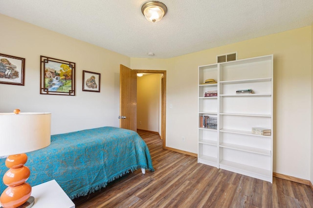 bedroom featuring wood finished floors, a textured ceiling, and baseboards