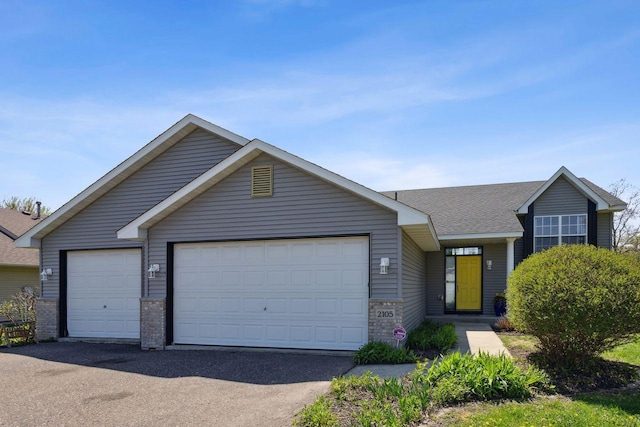 view of front of house featuring a garage, brick siding, driveway, and roof with shingles