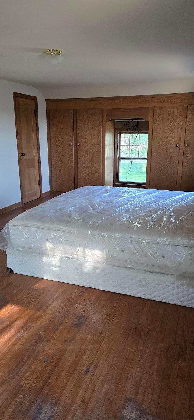 unfurnished bedroom with wood finished floors and baseboards