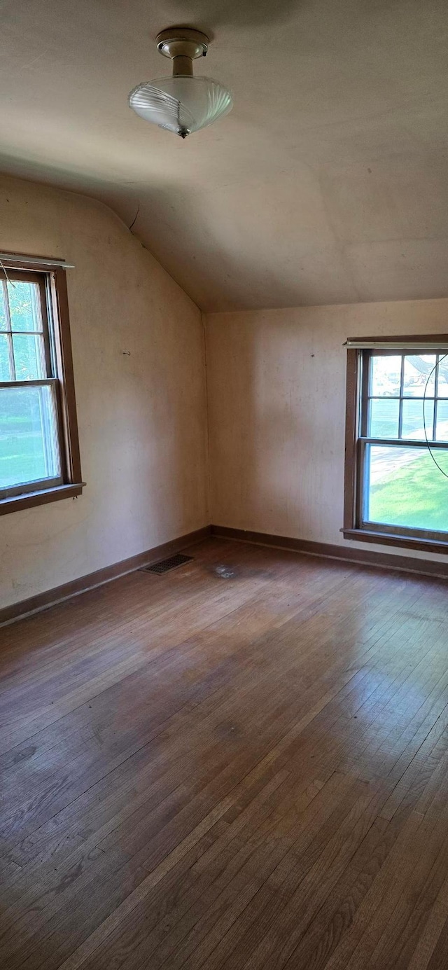 empty room with wood finished floors, lofted ceiling, and healthy amount of natural light
