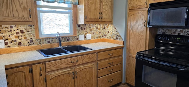 kitchen featuring black appliances, a sink, tasteful backsplash, and light countertops