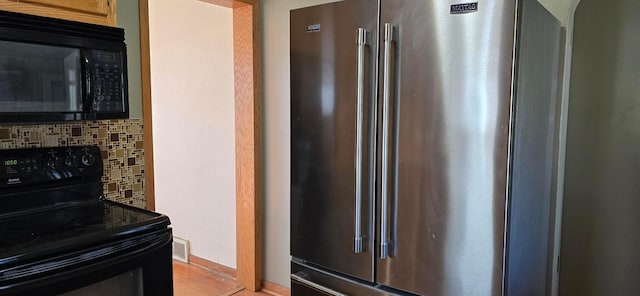 kitchen featuring black appliances, decorative backsplash, and arched walkways