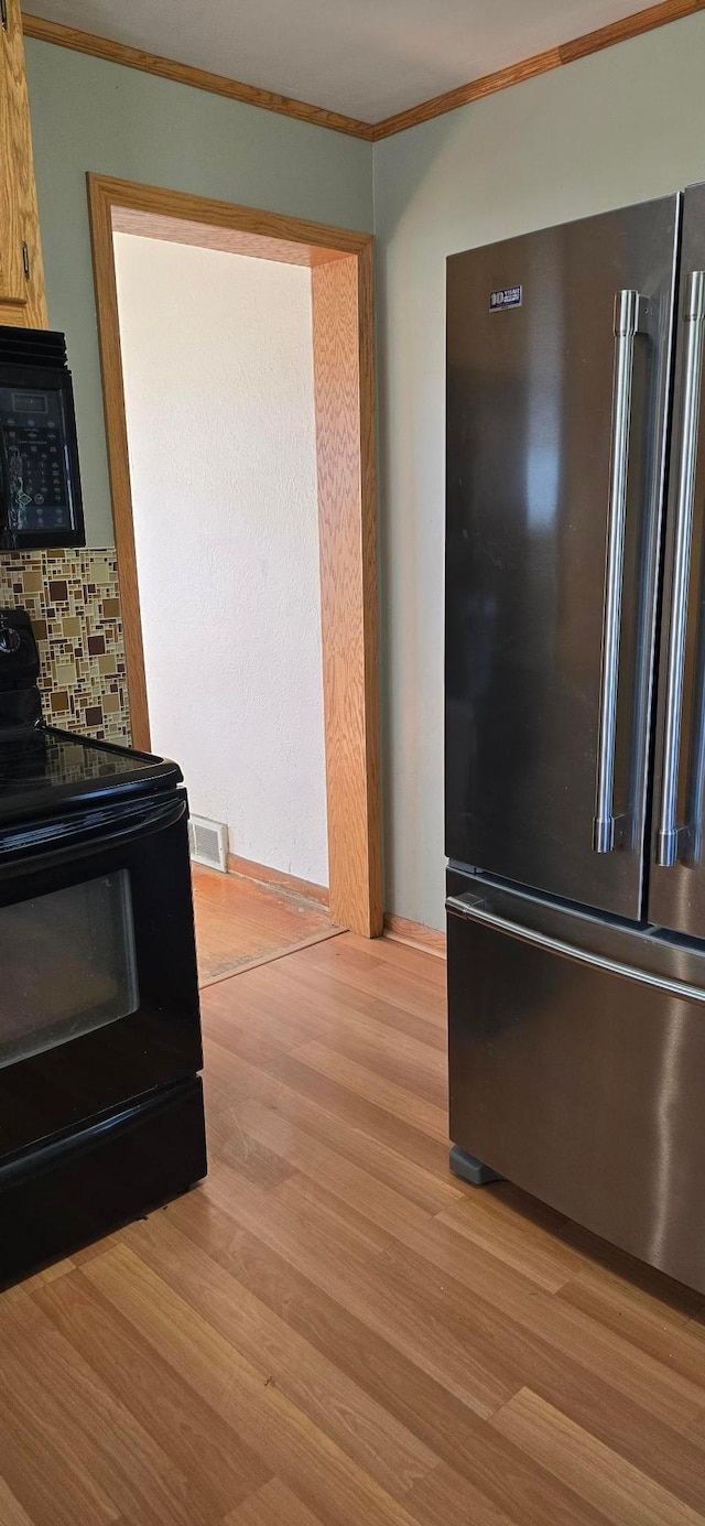 kitchen featuring black appliances, crown molding, light wood-style floors, and backsplash