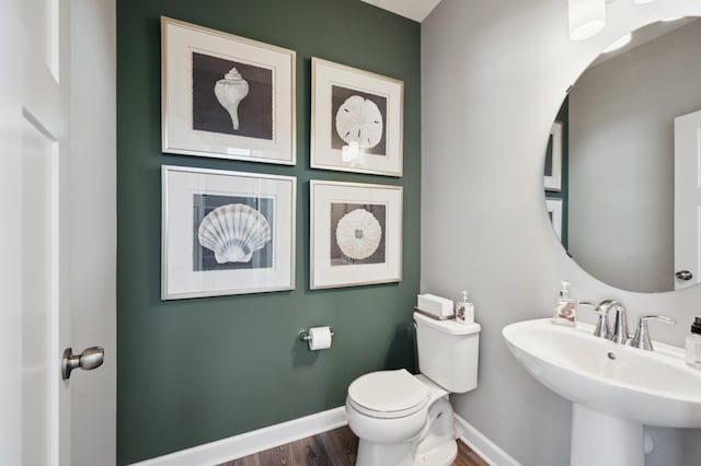 bathroom with wood finished floors, baseboards, a sink, and toilet
