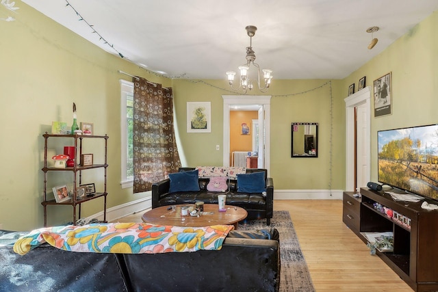 living area featuring light wood finished floors, radiator, baseboards, and a notable chandelier