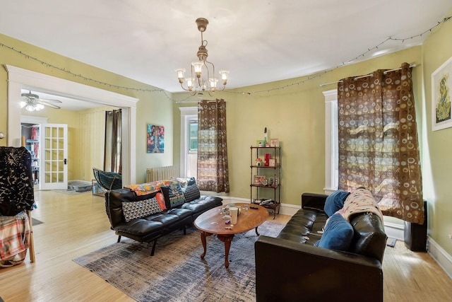 living room with rail lighting, radiator, light wood finished floors, and an inviting chandelier