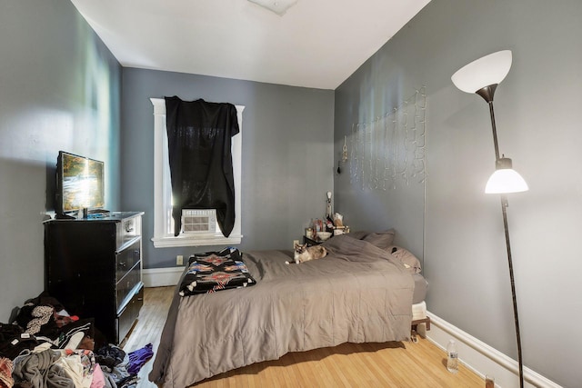 bedroom with cooling unit and wood finished floors