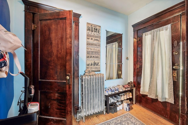 hall with radiator heating unit and wood finished floors