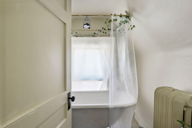 full bathroom with radiator and a tub