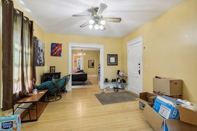 entryway with light wood-style flooring, a chandelier, ceiling fan, and baseboards