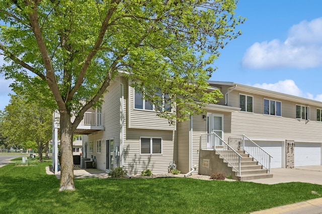 view of front of home featuring concrete driveway, a balcony, a garage, and a front yard